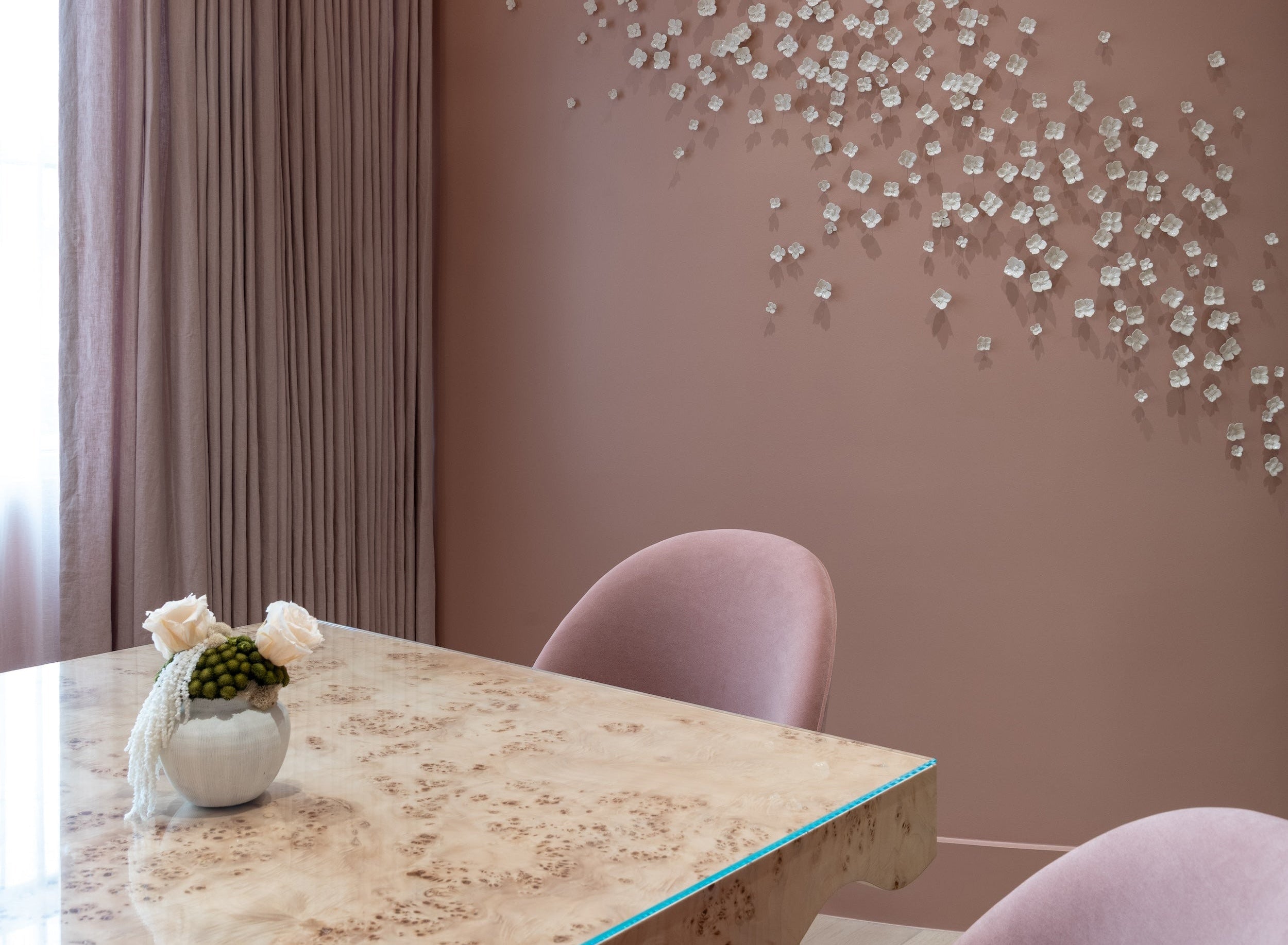 Spa area with a marble table and pink chairs against a wall with decorative white elements.